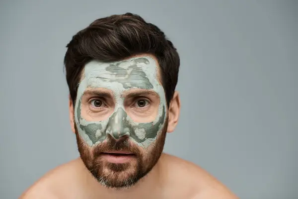 Alluring man wearing a facial mask, skincare. — Stock Photo