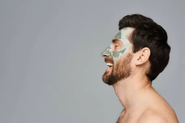 Shirtless man showcases a face mask, embracing his skincare routine. — Stock Photo