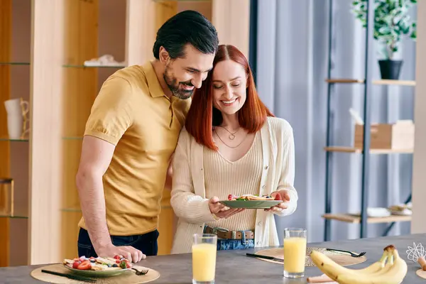 Una coppia elegante si gode uno spuntino nella loro cucina moderna, condividendo una banana insieme. — Foto stock