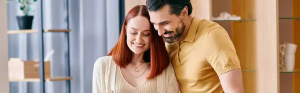Ein bärtiger Mann und eine rothaarige Frau umarmen sich zärtlich in einem modernen Wohnzimmer und drücken Zuneigung und Nähe aus. — Stockfoto