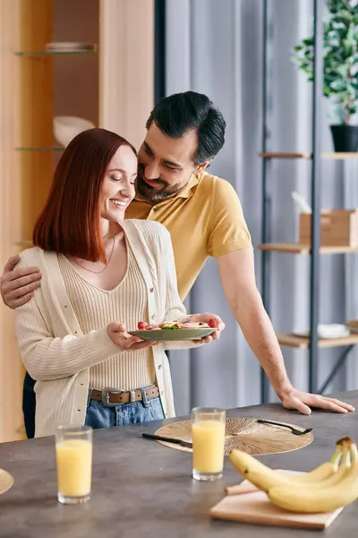 A redhead woman and a bearded man enjoying a cozy breakfast together in a modern kitchen. — Stock Photo
