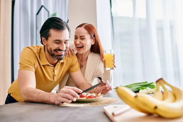 Красивая взрослая пара, рыжая женщина и бородатый мужчина, наслаждаются здоровым салатом в своей современной квартире. — стоковое фото