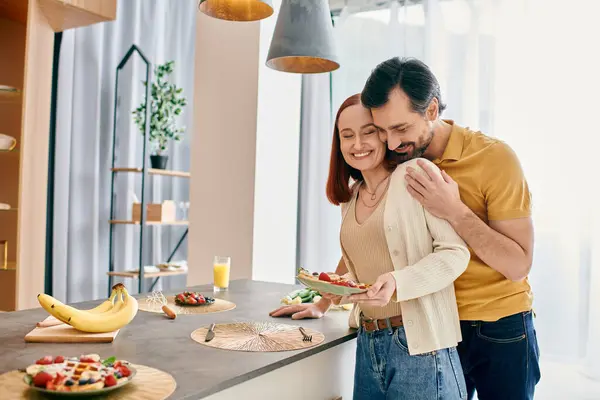 A bearded man and a redhead woman enjoy a cozy breakfast together in a modern apartment kitchen. — Stock Photo