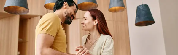 A redhead woman and bearded man stand in front of a wall in a modern apartment, spending quality time together at home. — Stock Photo