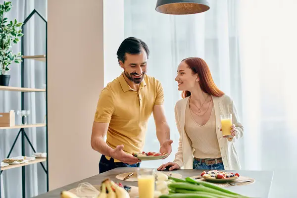 A redhead woman and bearded man enjoy breakfast together in a modern kitchen. — Stock Photo