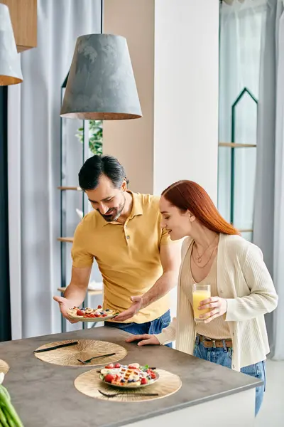 Uma mulher ruiva e um homem barbudo desfrutando de uma refeição juntos em uma cozinha moderna apartamento. — Fotografia de Stock