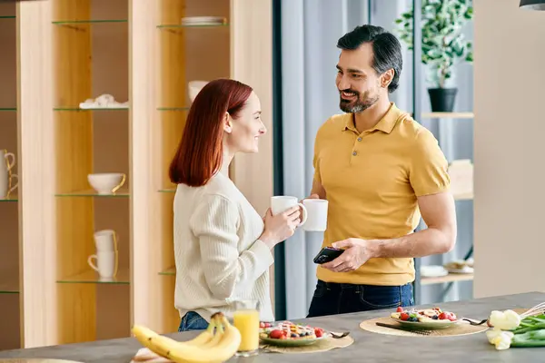 Une belle rousse et un homme barbu engageant une conversation sincère dans une cuisine moderne. — Photo de stock