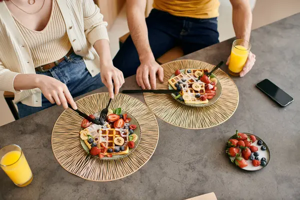 A beautiful adult couple spending quality time together while eating breakfast at a table in a modern apartment. — Stock Photo