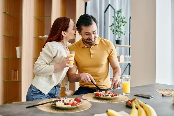 Eine rothaarige Frau und ein bärtiger Mann genießen gemeinsam einen Salat in einer modernen Küche und genießen einen Moment der gemeinsamen gesunden Ernährung. — Stockfoto