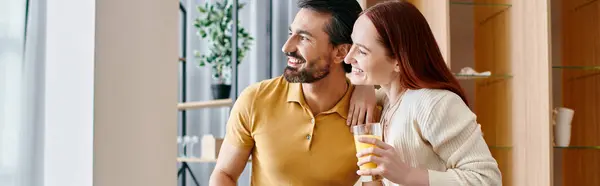 A beautiful adult couple, a redhead woman and a bearded man, smiling at each other in their modern living room. — Stock Photo