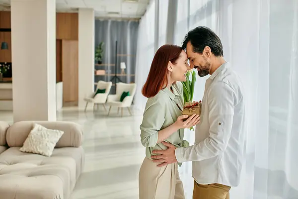 A young man and woman, a redhead woman and bearded man, stand together in a living room of a modern apartment, spending quality time together. — Stock Photo