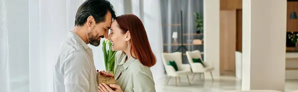 A redhead woman and bearded man share a tender kiss in a contemporary living room, surrounded by modern decor. — Stock Photo