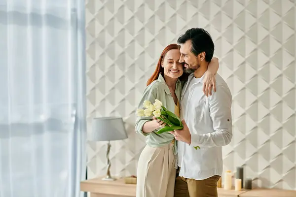 A beautiful adult couple, a redhead woman, and a bearded man sharing an intimate moment, hugging in their modern living room. — Stock Photo