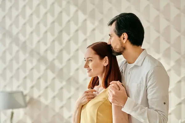 Un couple adulte élégant, une femme rousse et un homme barbu, debout ensemble devant un mur blanc minimaliste. — Photo de stock