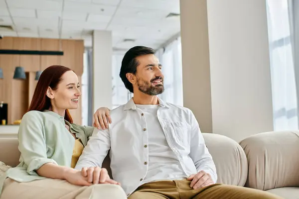 Красивая взрослая пара, рыжая женщина и бородатый мужчина, наслаждающиеся уютным моментом вместе на современном диване в гостиной. — стоковое фото