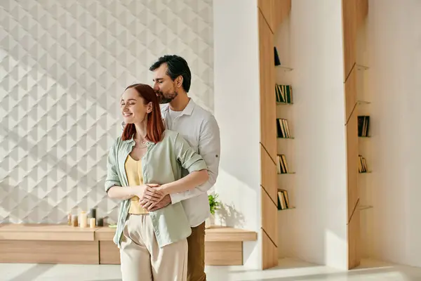 A redheaded woman and bearded man stand in a modern living room, enjoying each others company and the stylish decor. — Stock Photo