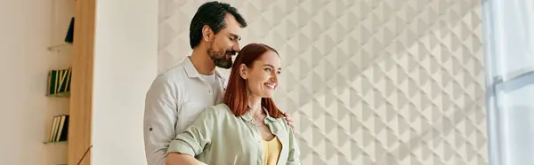 A stylish redhead woman and a bearded man stand together in front of a trendy wall in a modern apartment. — Stock Photo