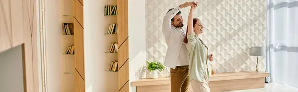 A beautiful adult couple, a redhead woman and a bearded man, dancing together in a modern living room. — Stock Photo