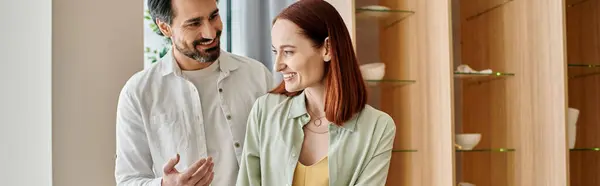 A bearded man and a redhead woman standing in a modern apartment setting. — Stock Photo
