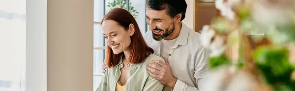 Un beau couple d'adultes, une femme rousse et un homme barbu, étreignant dans leur appartement moderne. — Photo de stock