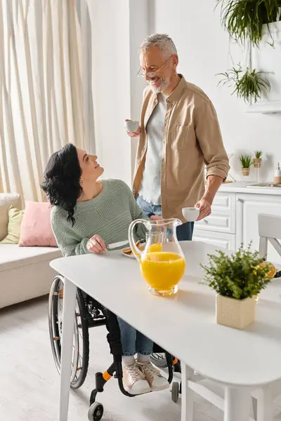 Une femme handicapée en fauteuil roulant profite d'un moment de calme avec son mari dans le confort de leur salon à la maison. — Photo de stock