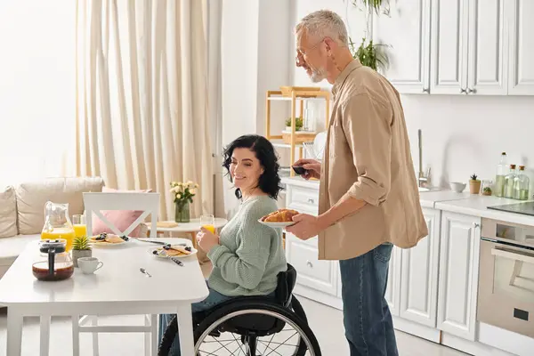 Eine behinderte Frau im Rollstuhl und ihr Mann bereiten zu Hause in ihrer Küche gemeinsam ein Essen zu. — Stockfoto