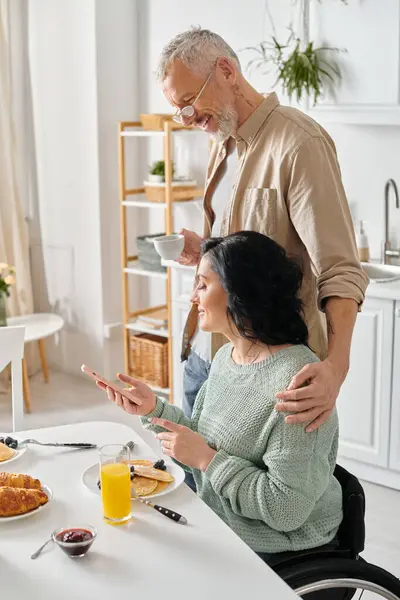 Una coppia sposata, il marito e la moglie disabile, condividono un pasto insieme a un tavolo da cucina nella loro casa. — Foto stock