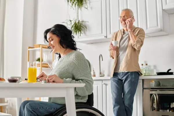 A disabled woman in a wheelchair and her husband together in their home kitchen. — Stock Photo