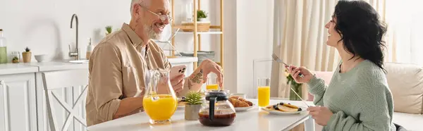 Um homem e uma mulher com deficiência em uma cadeira de rodas compartilham uma refeição tranquila da manhã em uma mesa de cozinha aconchegante em sua casa. — Fotografia de Stock