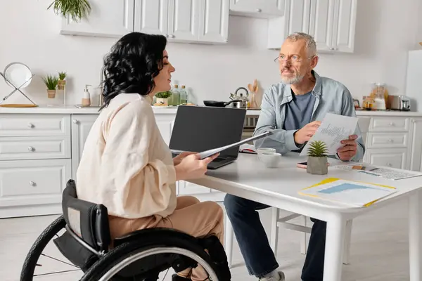 Family budget of man and disabled woman reviewing documents at kitchen table — Stock Photo