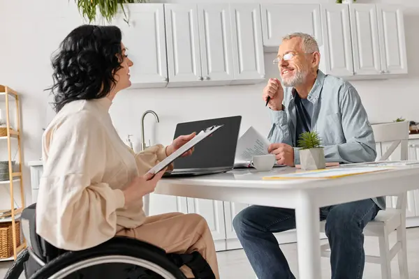 A man and a woman in wheelchairs chatting in the kitchen at home. — Stock Photo