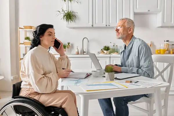 Um homem e uma mulher sentam-se em uma mesa, focados em uma tela de laptop, envolvidos em trabalho colaborativo em sua cozinha em casa.. — Fotografia de Stock