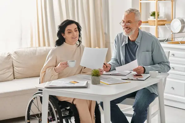 Eine behinderte Frau im Rollstuhl sitzt mit ihrem Mann an einem Tisch und diskutiert über das Familienbudget — Stockfoto
