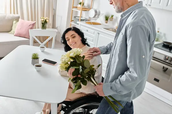 A man stands by his wifes wheelchair in their kitchen, showing unwavering support and love. — Stock Photo