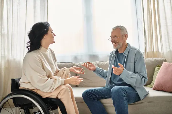 Ein Mann im Rollstuhl diskutiert mit einer behinderten Frau im Rollstuhl in einem gemütlichen Wohnzimmer. — Stockfoto