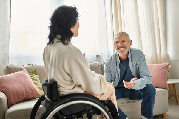 Une femme en fauteuil roulant engage une conversation avec son mari dans leur cadre confortable salon. — Photo de stock