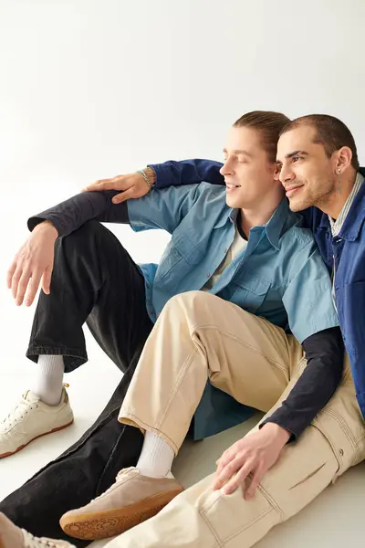 Two men sitting closely on the ground, exuding warmth and camaraderie. — Stock Photo