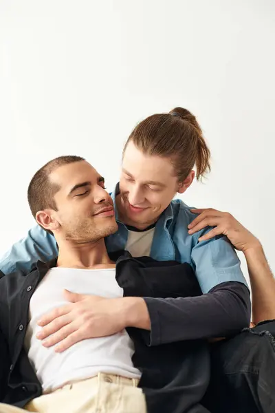 A man sits on top of another man on a couch in a loving and intimate moment. — Stock Photo