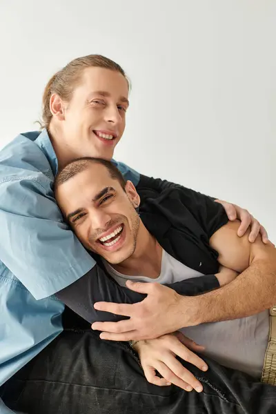 Dos hombres muestran afecto al sentarse de cerca en un sofá, abrazándose amorosamente.. - foto de stock