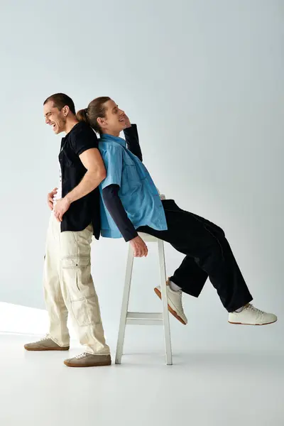 A man seated on a stool, another man standing beside him. — Stock Photo