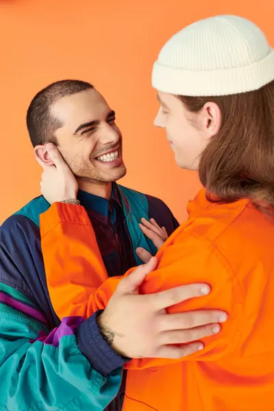 An orange-jacketed man lovingly hugs his boyfriend. — Stock Photo