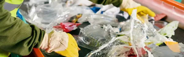 A young volunteer in a green shirt and yellow gloves sorts trash with eco-conscious individuals, united in their efforts. — Stock Photo