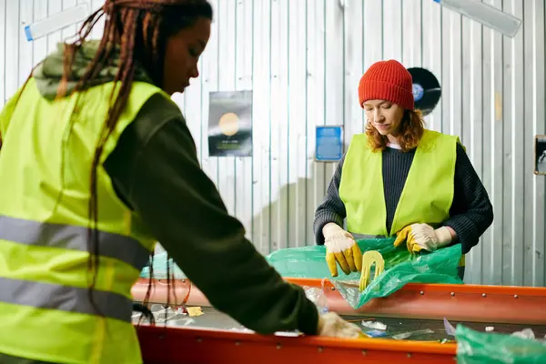 Two young women in yellow and green vests, sorting trash together as eco-conscious volunteers. - foto de stock