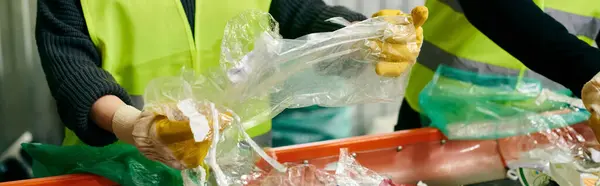 Young volunteers wearing gloves and safety vests stand together, holding bags of food for a community drive. — Stock Photo