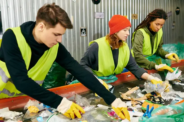 A group of eco-conscious young volunteers in safety vests and gloves sorting through garbage together. — Stock Photo