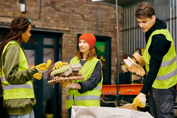 Group of young volunteers in gloves and safety vests, sorting trash together in a show of eco-consciousness. — Stock Photo