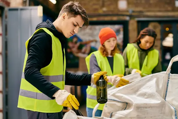 A group of eco-conscious young volunteers in yellow vests and gloves sorting trash together. — Stock Photo