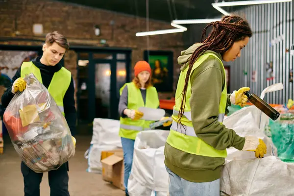 Young volunteers in gloves and safety vests sorting through a pile of garbage to promote environmental consciousness. — стокове фото