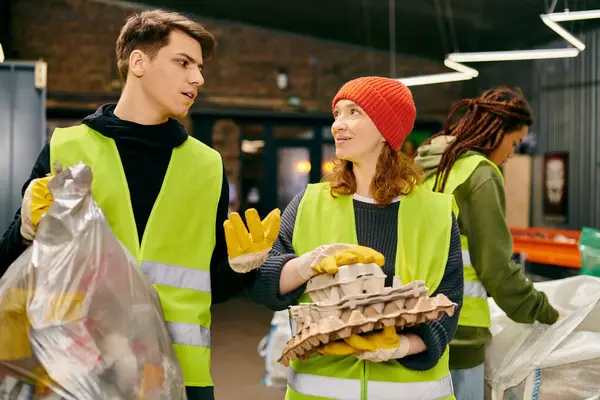 Eco-conscious people, in gloves and safety vests, stand together, sorting trash as young volunteers. — стоковое фото