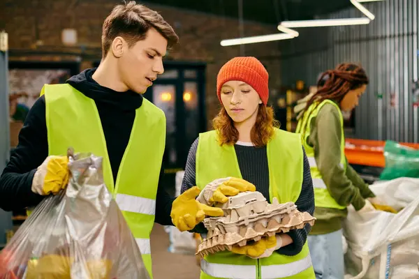 Young volunteers in gloves and safety vests work together to sort trash, demonstrating eco-conscious practices. — Stock Photo